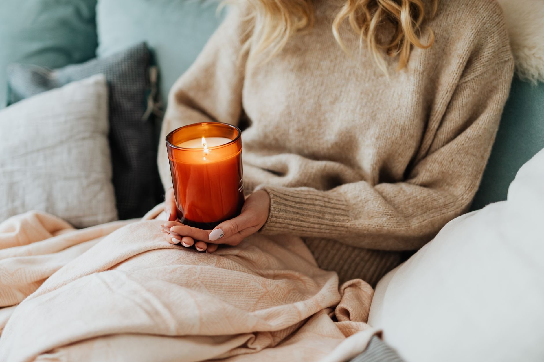A comforting indoor scene — woman holding a candle in a cozy, warmly lit room
